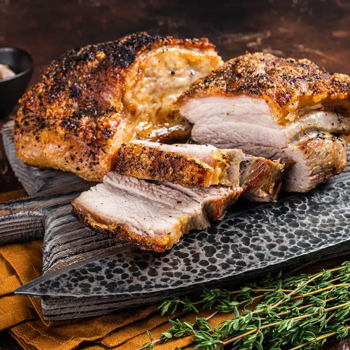 Roasted Pork belly bacon with crust on a wooden board. Dark background. Top view.