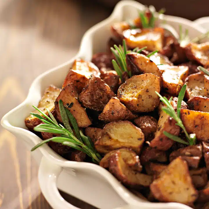 rosemary herb potatoes in white baking dish close up.