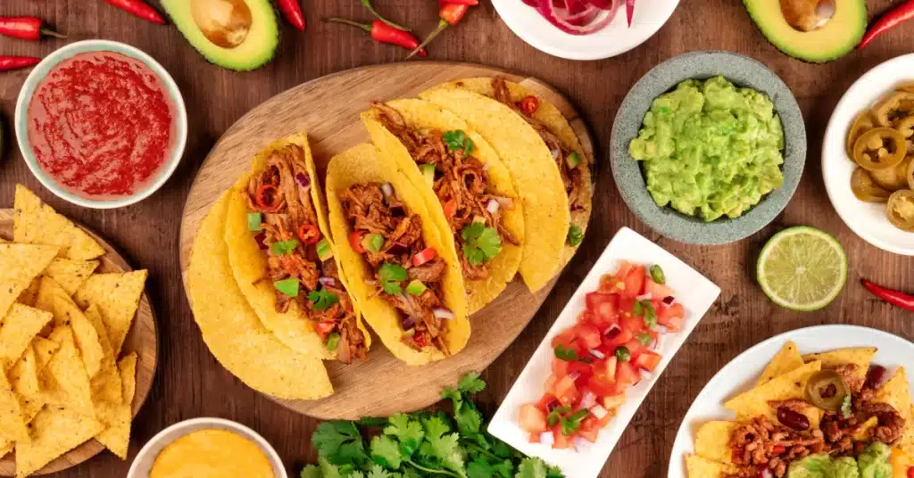 An image showing a delicious spread of tacos, guacamole, salsa, and toppings from Rooster's Rolling BBQ catering service.